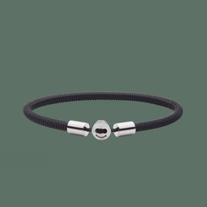 The Smile bracelet in black Silicon Rubber with stainless steel button clasp. Fully waterproof. Green background.
