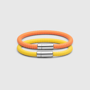 The Signature bracelet in yellow with stainless steel clasp. FKM fluoroelastomer rubber – Fully waterproof. Bundled together with the Signature Bracelet in orange on white background.