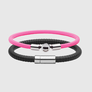 The Signature Bracelet in black with stainless steel clasp. FKM fluoroelastomer rubber – Fully waterproof. Bundled together with the Smile Bracelet in Neon Pink in silicon rubber, White background.