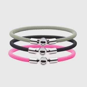 The Smile bracelet in Neon Pink Silicon Rubber with stainless steel button clasp, bundled with Smile Bracelet in Black and Light Green. Fully waterproof. White background.