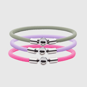 The Smile bracelet in Neon Pink Silicon Rubber with stainless steel button clasp, bundled with Smile Bracelet in Lavender and Light Green. Fully waterproof. White background.