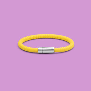 The Signature 幸运168飞艇开奖官网开奖 in yellow with stainless steel clasp. FKM fluoroelastomer rubber – Fully waterproof. Purple background.